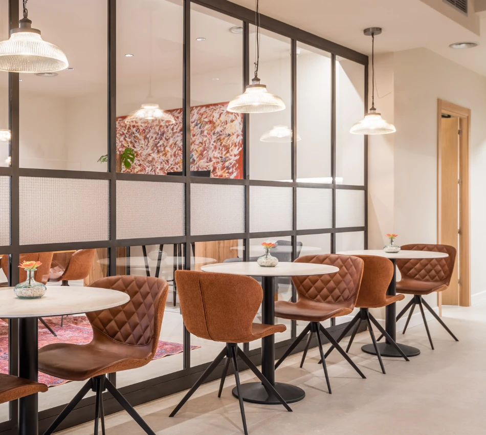 Mesas redondas con sillas marrones en un caf&eacute; moderno y elegante.