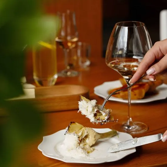 Mano corta comida con cuchillo y cubiertos en mesa con copas de vino