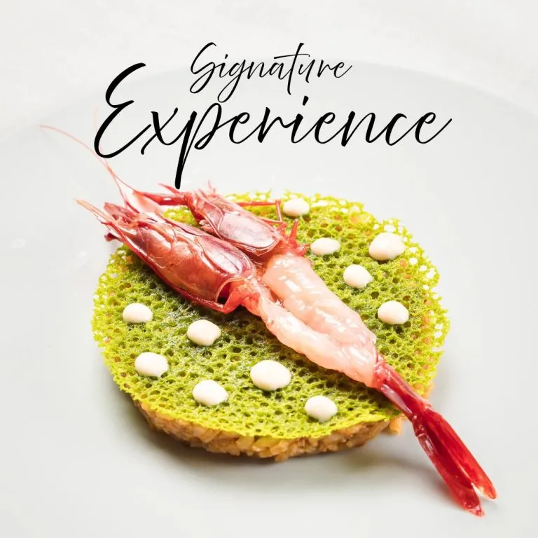Gambas sobre pan con esponja verde y peque&ntilde;as perlas blancas; &ldquo;Signature Experience&rdquo;.