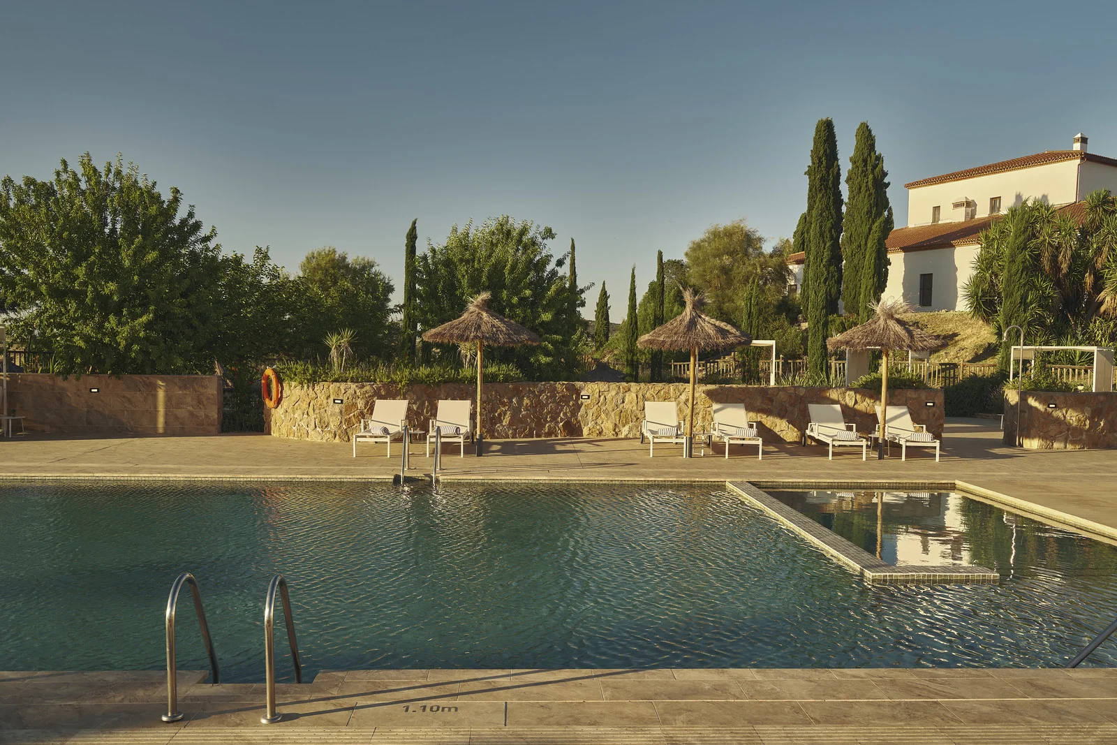 Piscina al aire libre con tumbonas, sombrillas y edificios de fondo