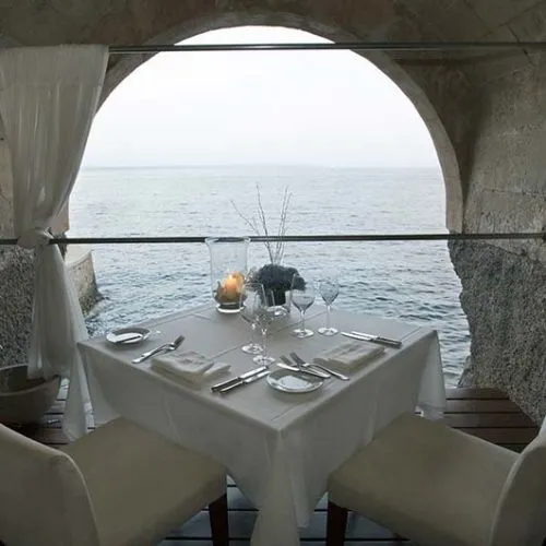 Mesa decorada frente al mar, a trav&eacute;s de un arco de piedra.