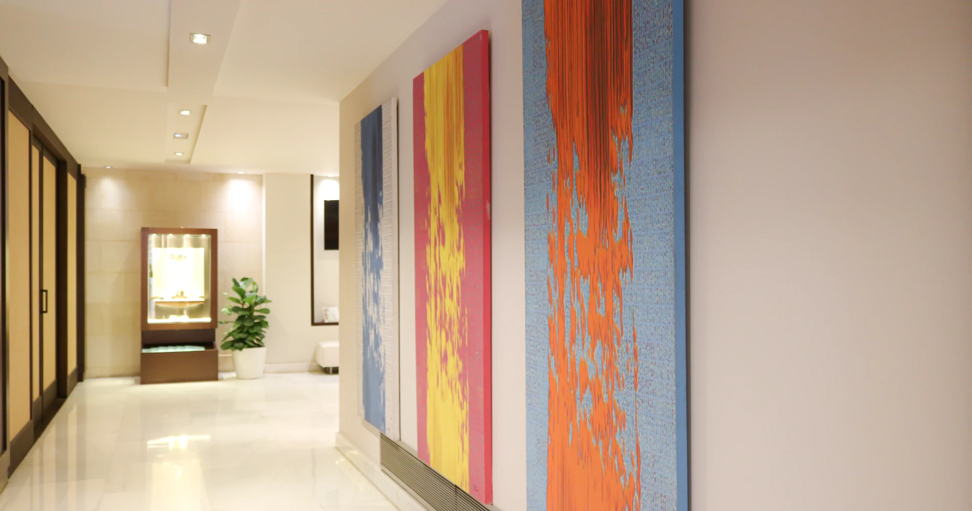 Pasillo moderno con paredes claras y cuadros abstractos rojo, azul y naranja