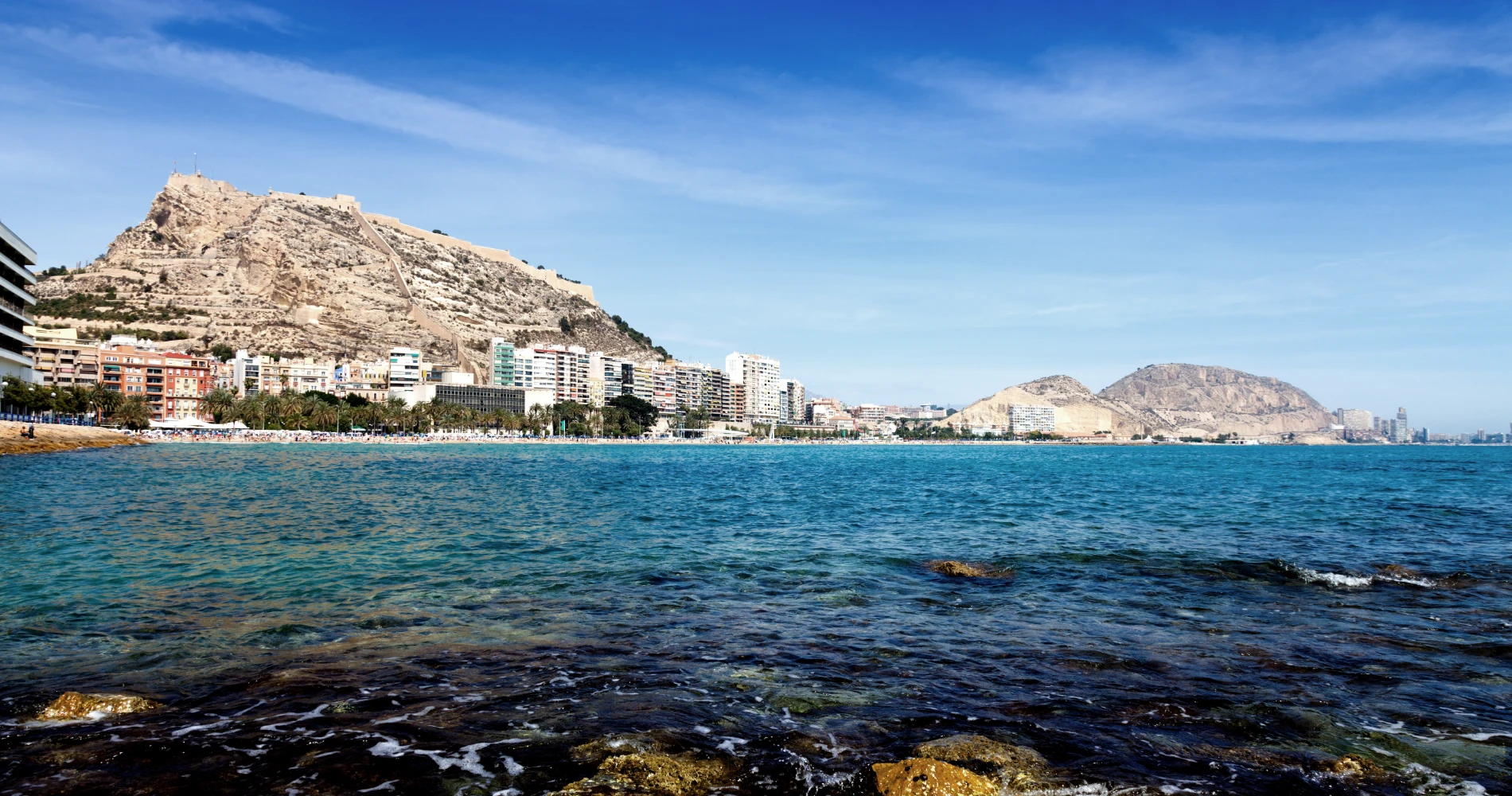 Vista de la costa con mar, ciudad y una monta&ntilde;a rocosa con fortaleza