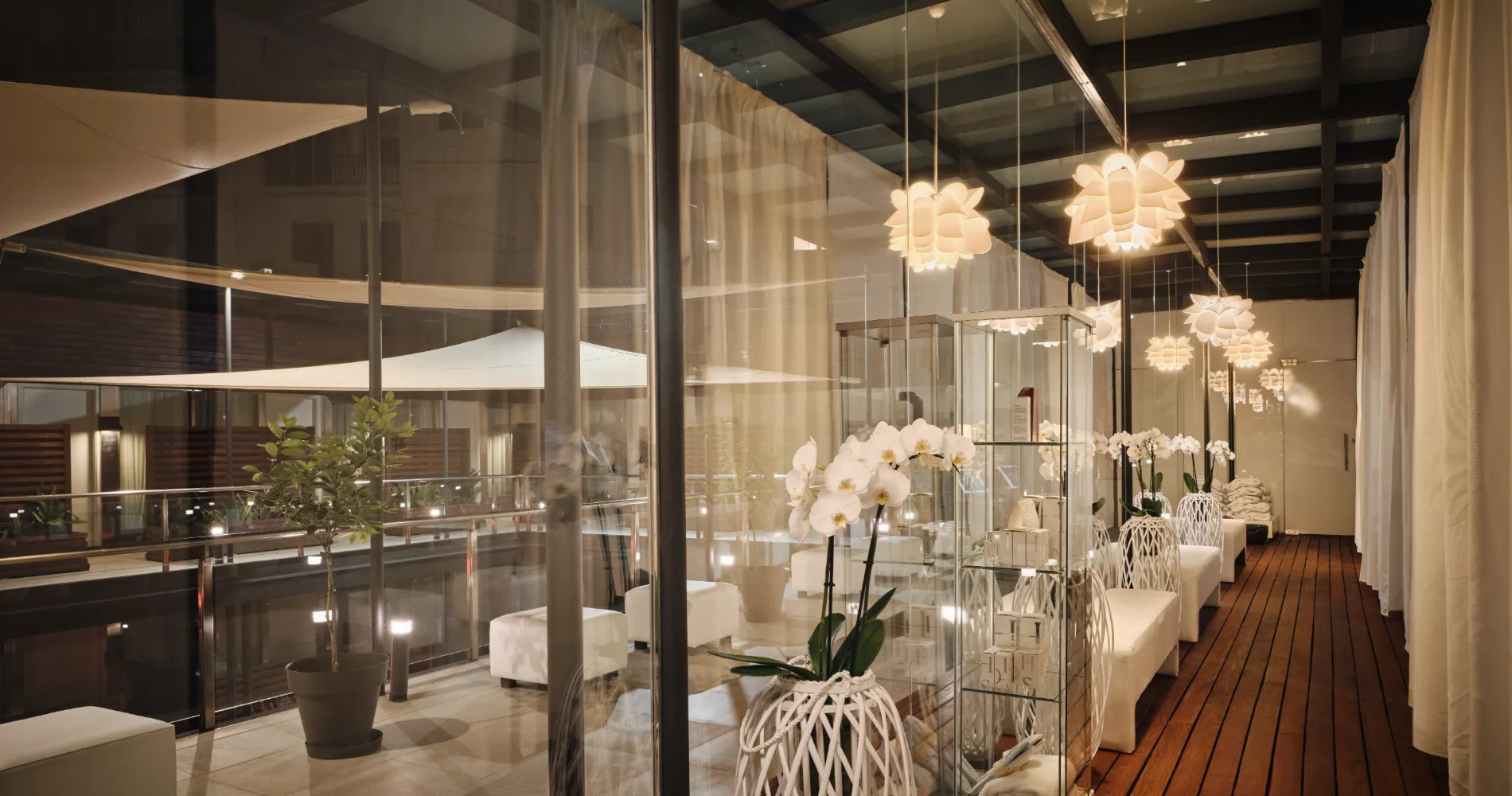 Interior de hotel con mesas, orqu&iacute;deas blancas y l&aacute;mparas colgantes decorativas