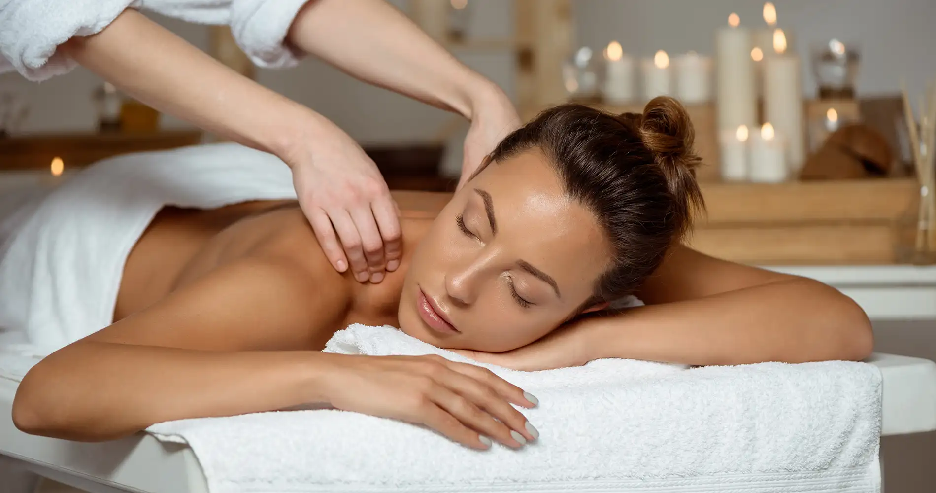 Masaje relajante en el spa a una mujer recostada, con toallas blancas