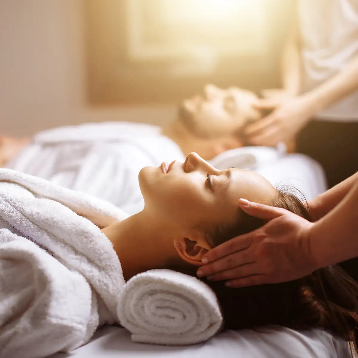 Mujer recibiendo masaje relajante con toallas, en un spa.