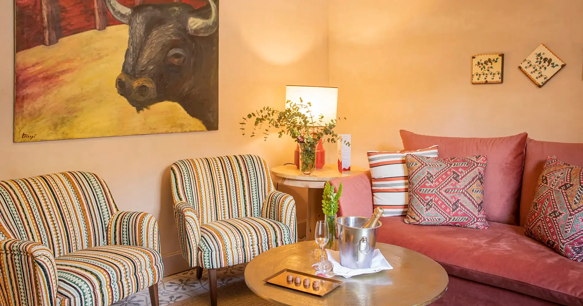 Sala acogedora con sof&aacute;s rosas, cojines estampados, mesa y pinturas decorativas
