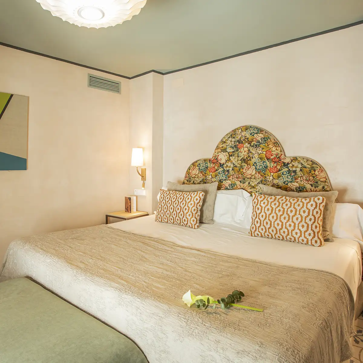 Dormitorio con cama doble, almohadas decorativas y l&aacute;mpara de techo blanca