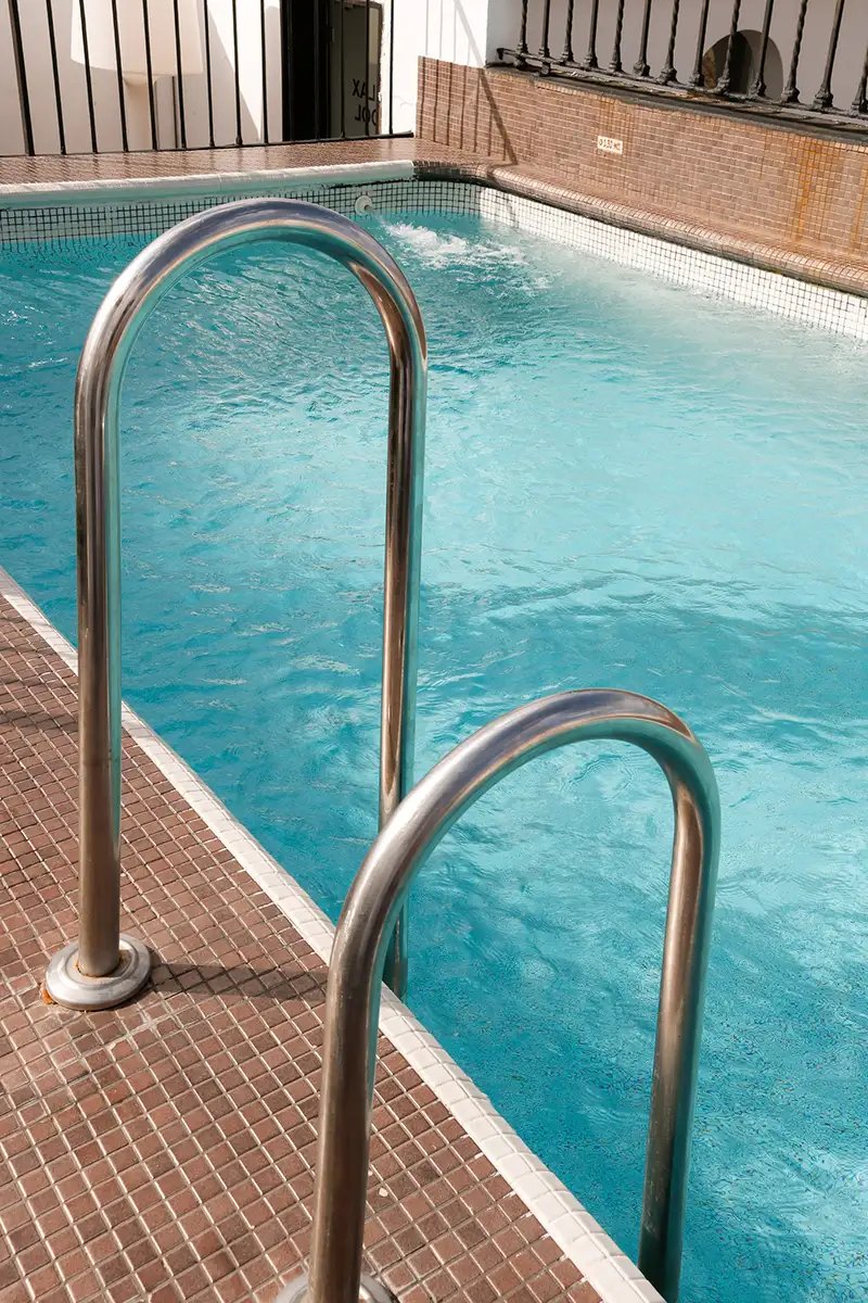 Piscina interior con escaleras de acero y agua azul turquesa
