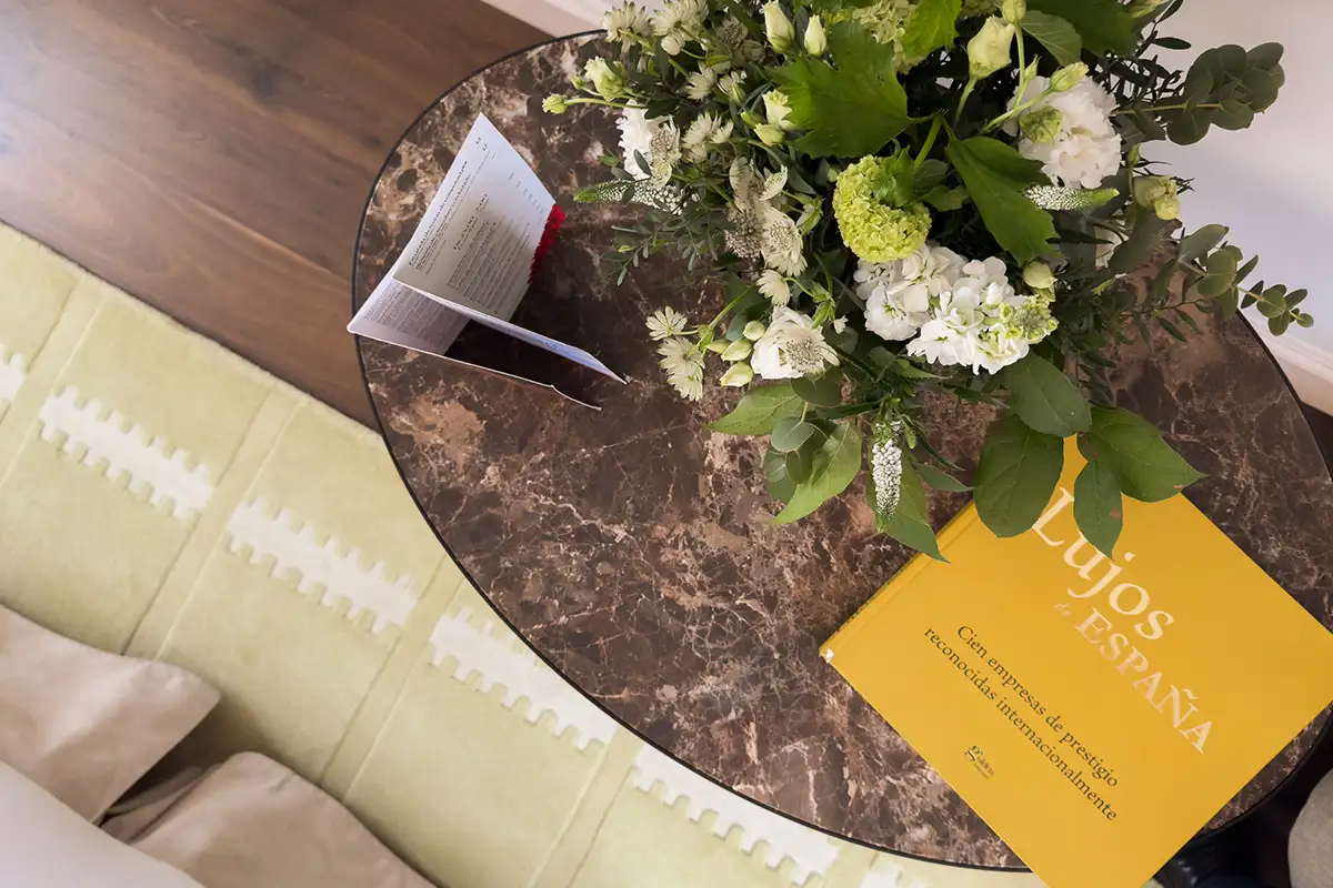 Ramo de flores y tarjeta amarilla &ldquo;SON-ESTARNA&rdquo; sobre mesa de m&aacute;rmol
