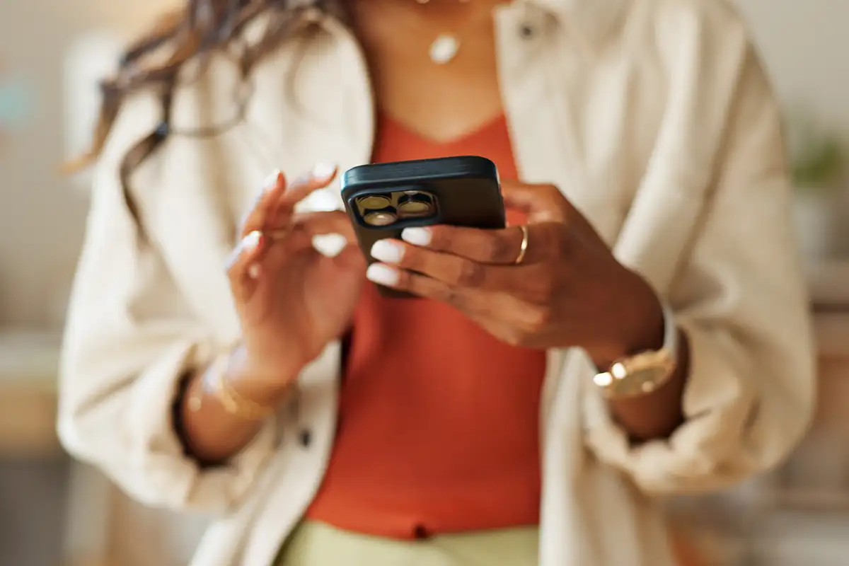 Mujer con tel&eacute;fono inteligente, posando con estilo en interior.