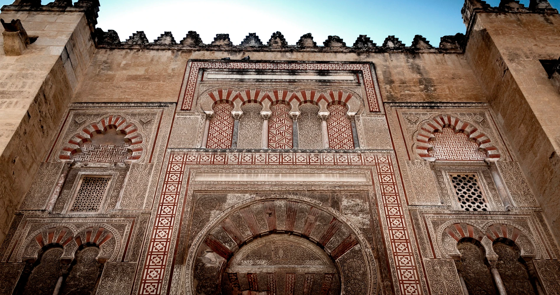 Fachada de mezquita con arcos y mosaicos geom&eacute;tricos, vista desde abajo