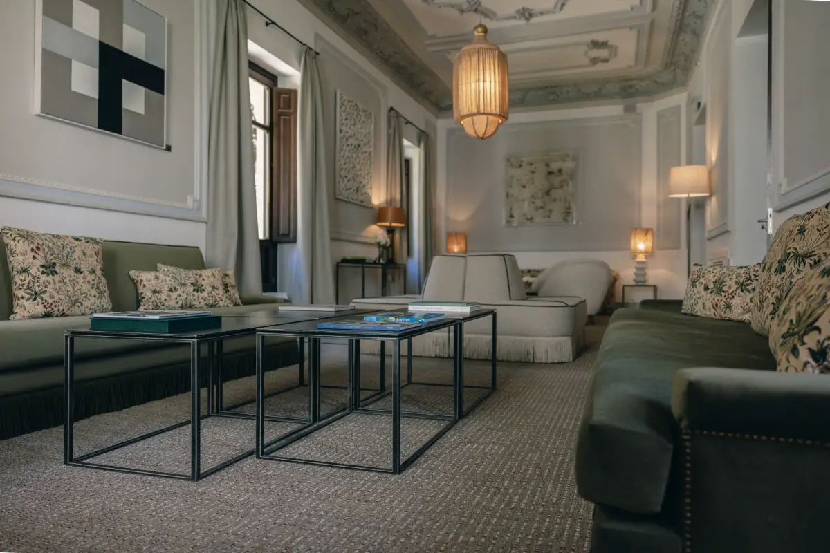 Sala de estar elegante con sof&aacute;s, mesa de centro de vidrio y l&aacute;mparas colgantes