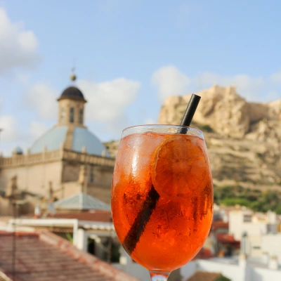 C&oacute;ctel rojo con fondo de ciudad y monta&ntilde;as al atardecer