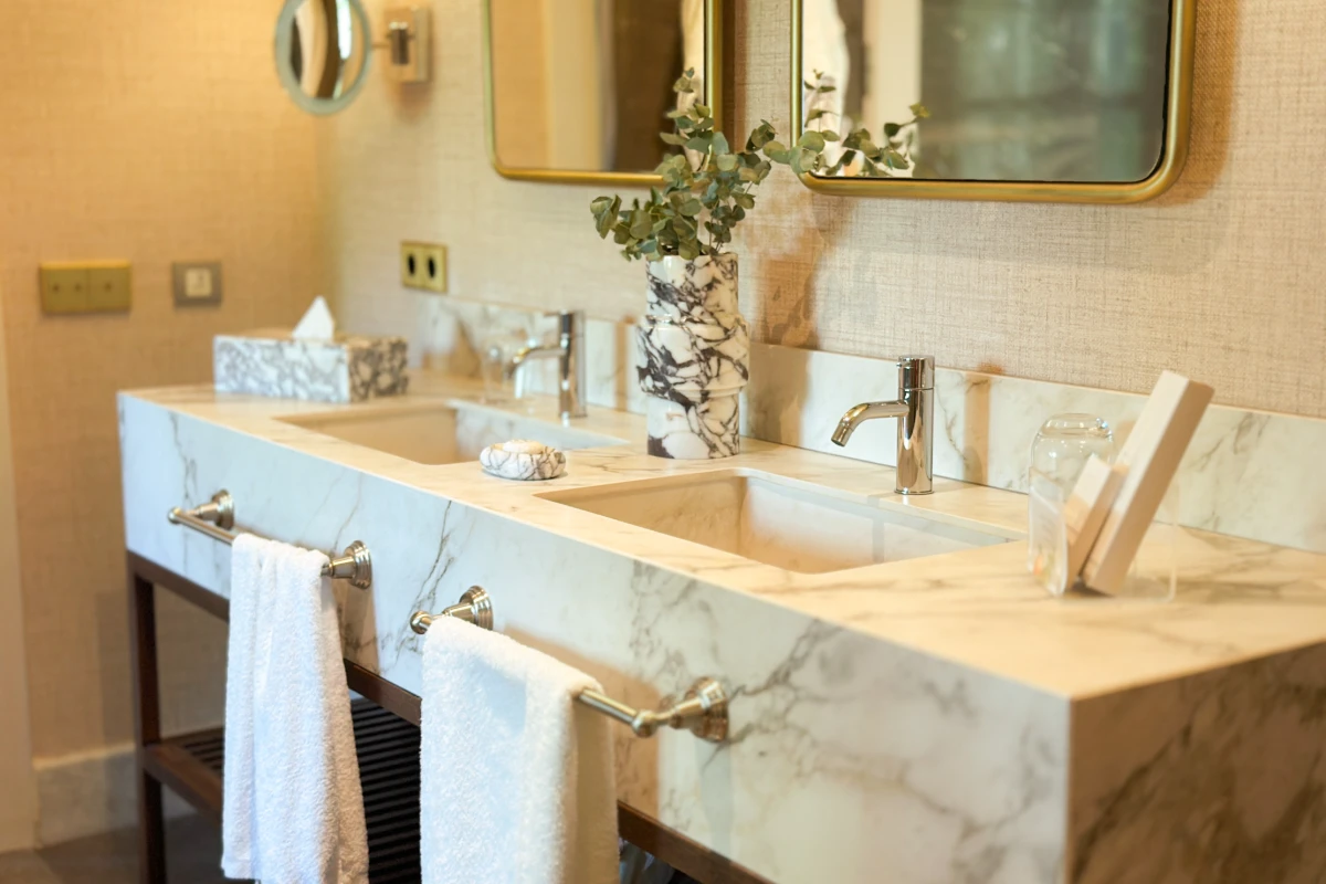 Lavabo doble con grifos de acero y espejo en ba&ntilde;o moderno con decoraci&oacute;n vegetal