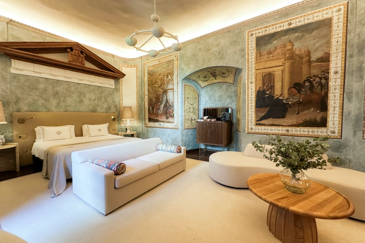 Habitaci&oacute;n de hotel elegante con cama, sof&aacute; y cuadros decorativos en la pared