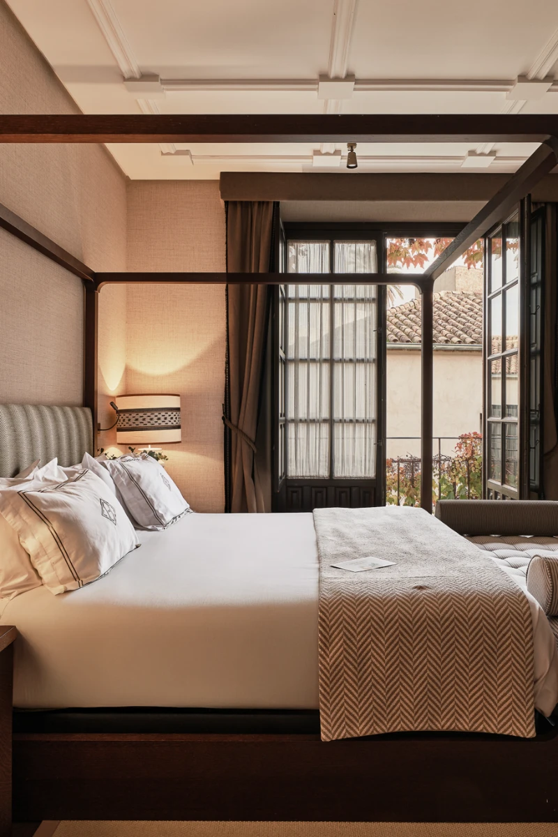 Dormitorio moderno con cama, cortinas y vista a patio exterior.