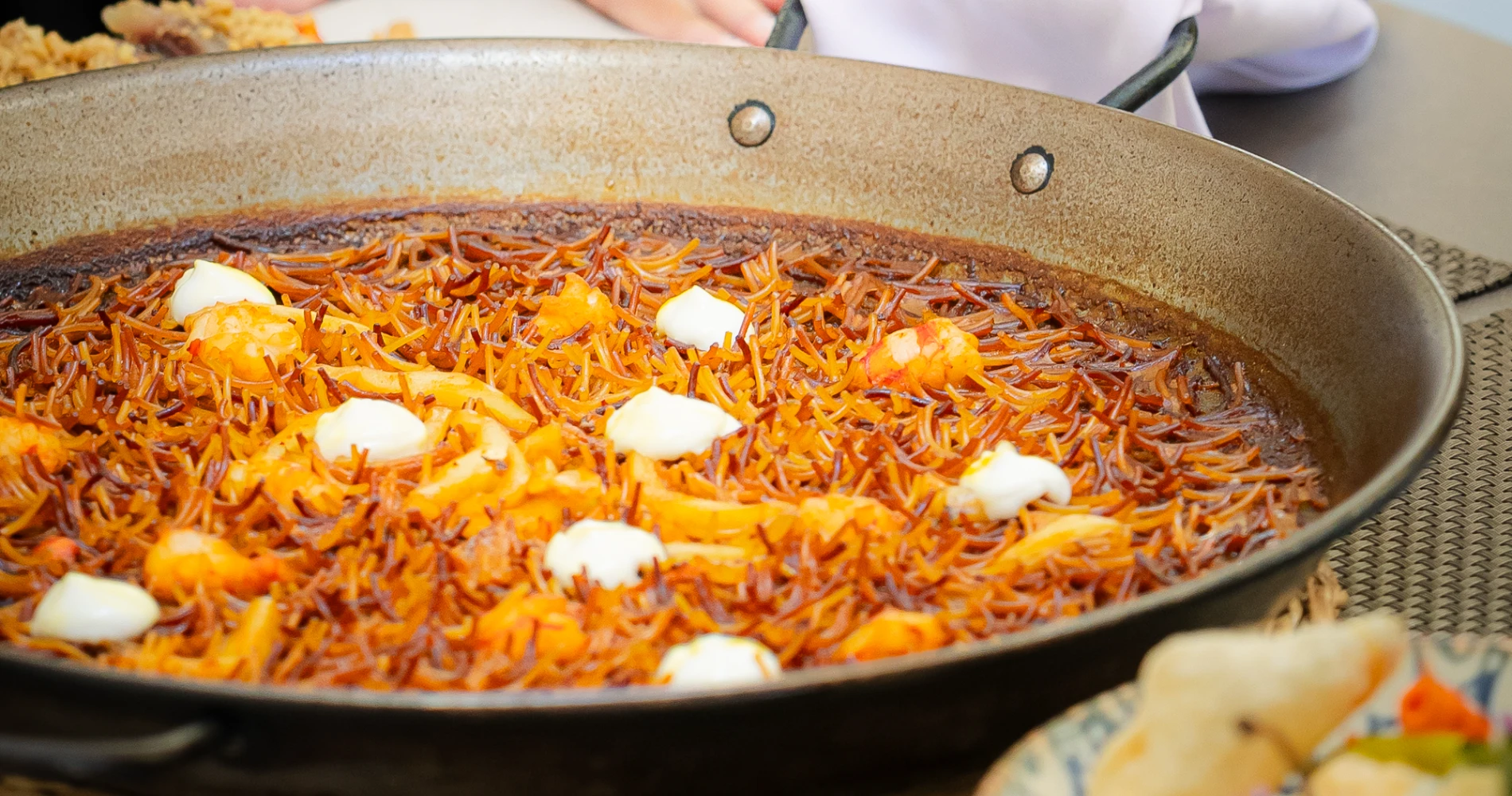 Paella de marisco en sart&eacute;n con zanahoria rallada y trozos de huevo cocido