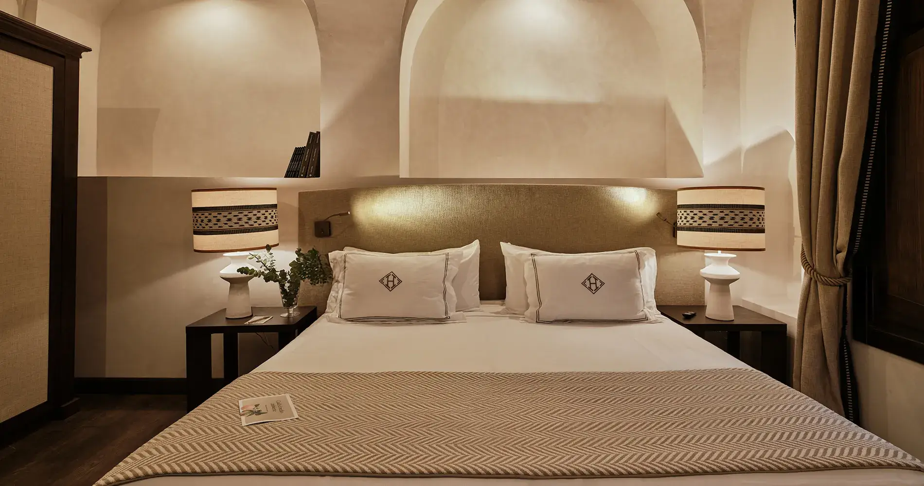 Dormitorio con cama doble, almohadas blancas y l&aacute;mparas empotradas decorativas