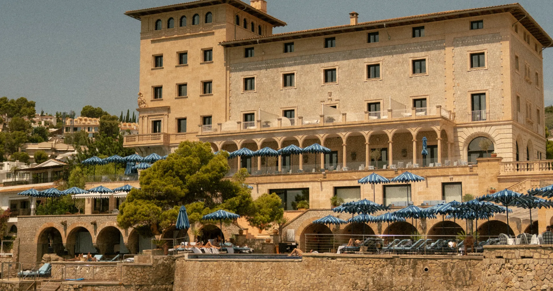 Hotel de estilo mediterr&aacute;neo con sombrillas azules y arcos, vista exterior