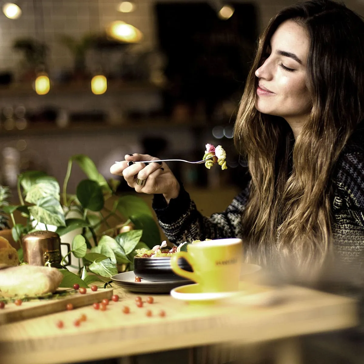 Mujer degustando una ensalada con palillos, en una mesa con vegetales