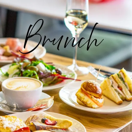 Mesa con brunch y copa de vino, platos variados sobre madera.