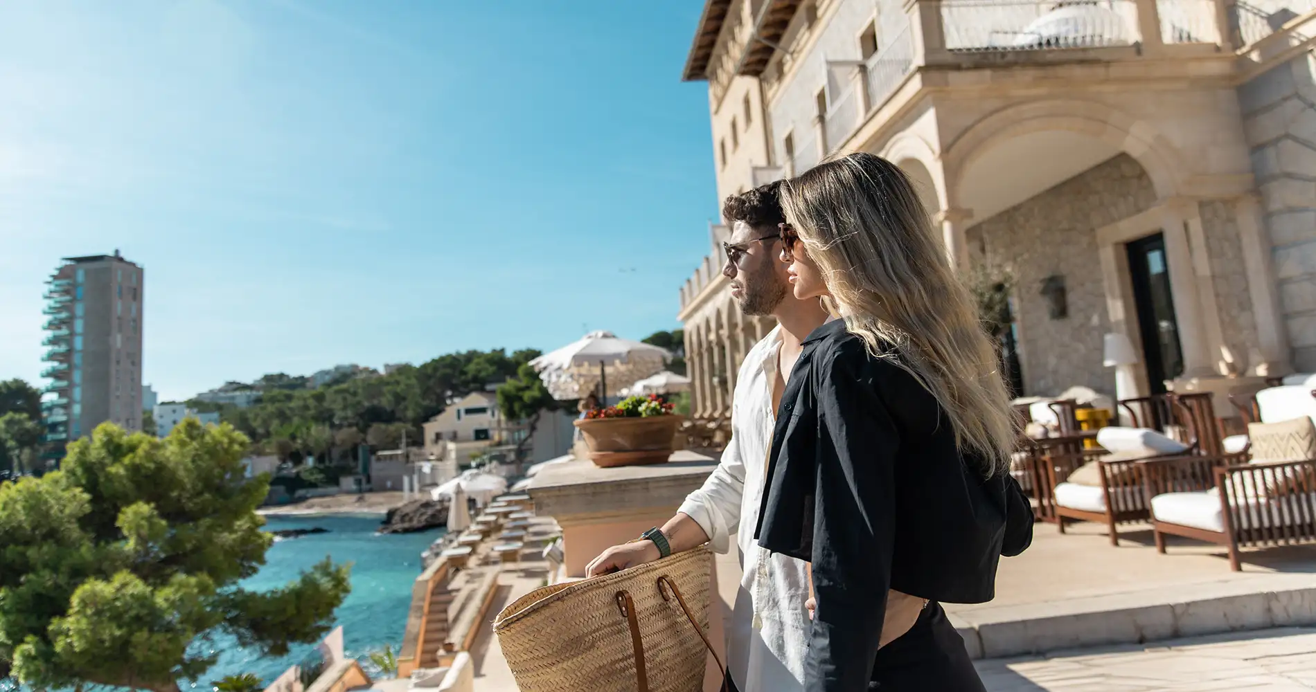 Pareja paseando en un balc&oacute;n con vista al r&iacute;o y edificios hist&oacute;ricos