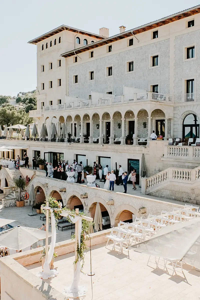 Patio de boda con sillas blancas y edificio de piedra y arcos