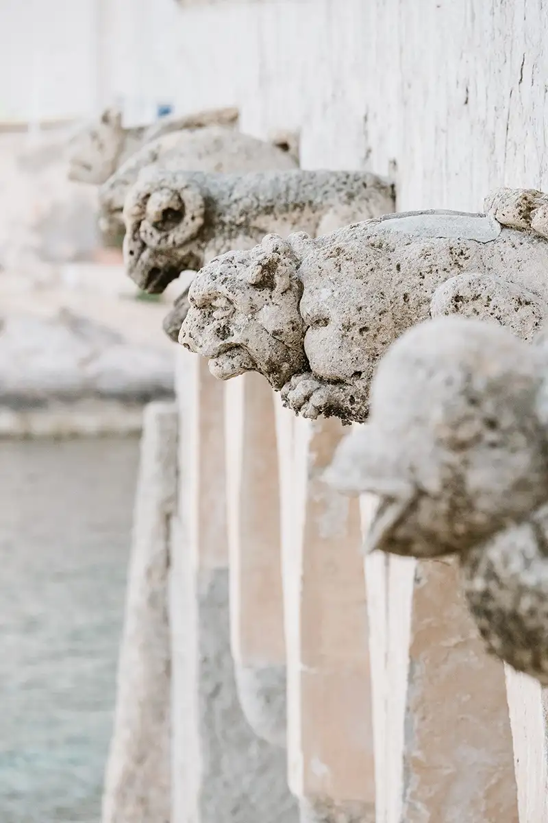 Escultura de piedra con boca de cr&aacute;neo sobre fuente blanca, en primer plano