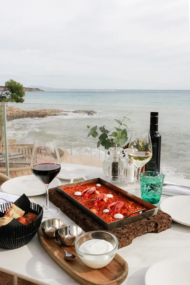 Mesa con vino y aperitivos frente al mar y olas en la costa