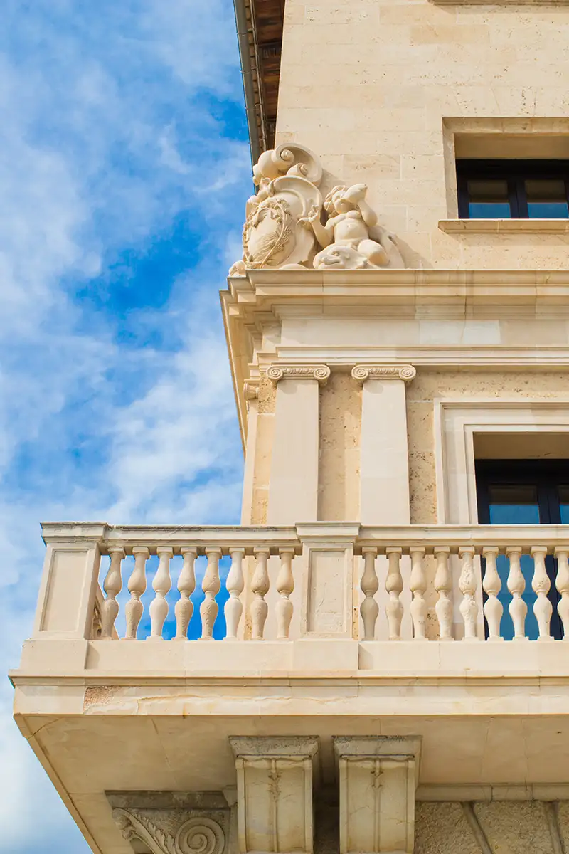 Fachada cl&aacute;sica de edificio con esculturas ornamentales bajo cielo azul