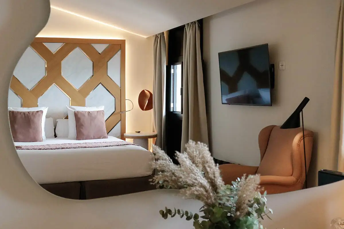 Dormitorio moderno con cama, l&aacute;mpara, TV y sof&aacute;, vista desde interior.
