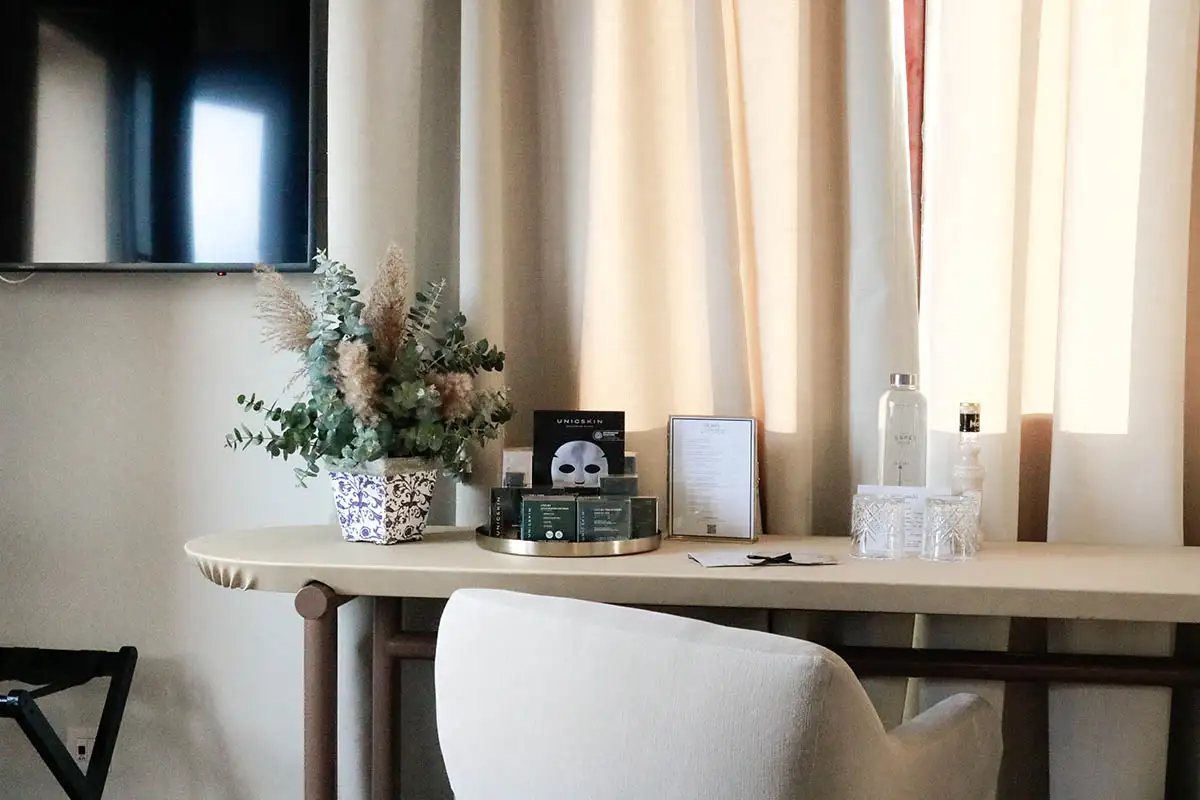 Mesa de madera con plantas y productos junto a cortinas claras y ventana