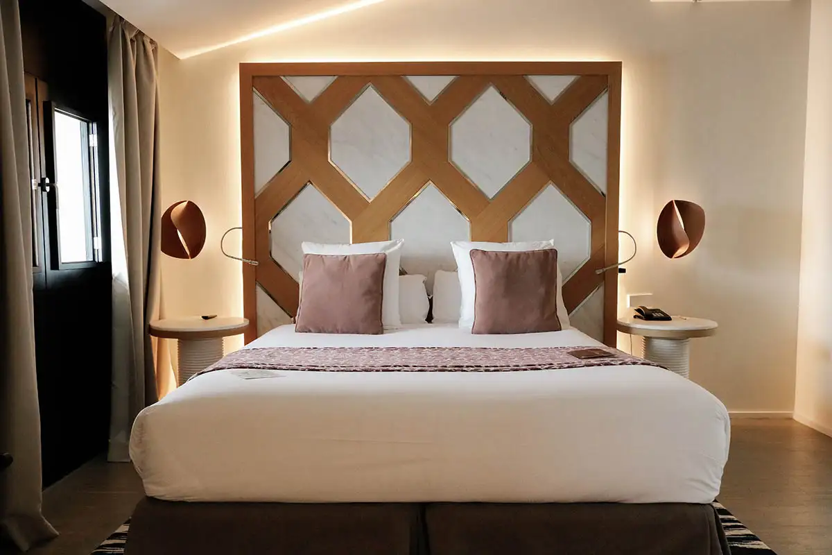 Dormitorio moderno con cama doble, cabecero geom&eacute;trico de madera y luces LED