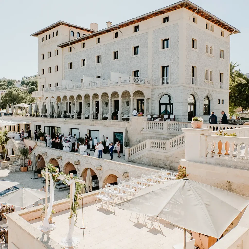 Edificio blanco de estilo cl&aacute;sico con arcos y terraza, evento bajo carpas.