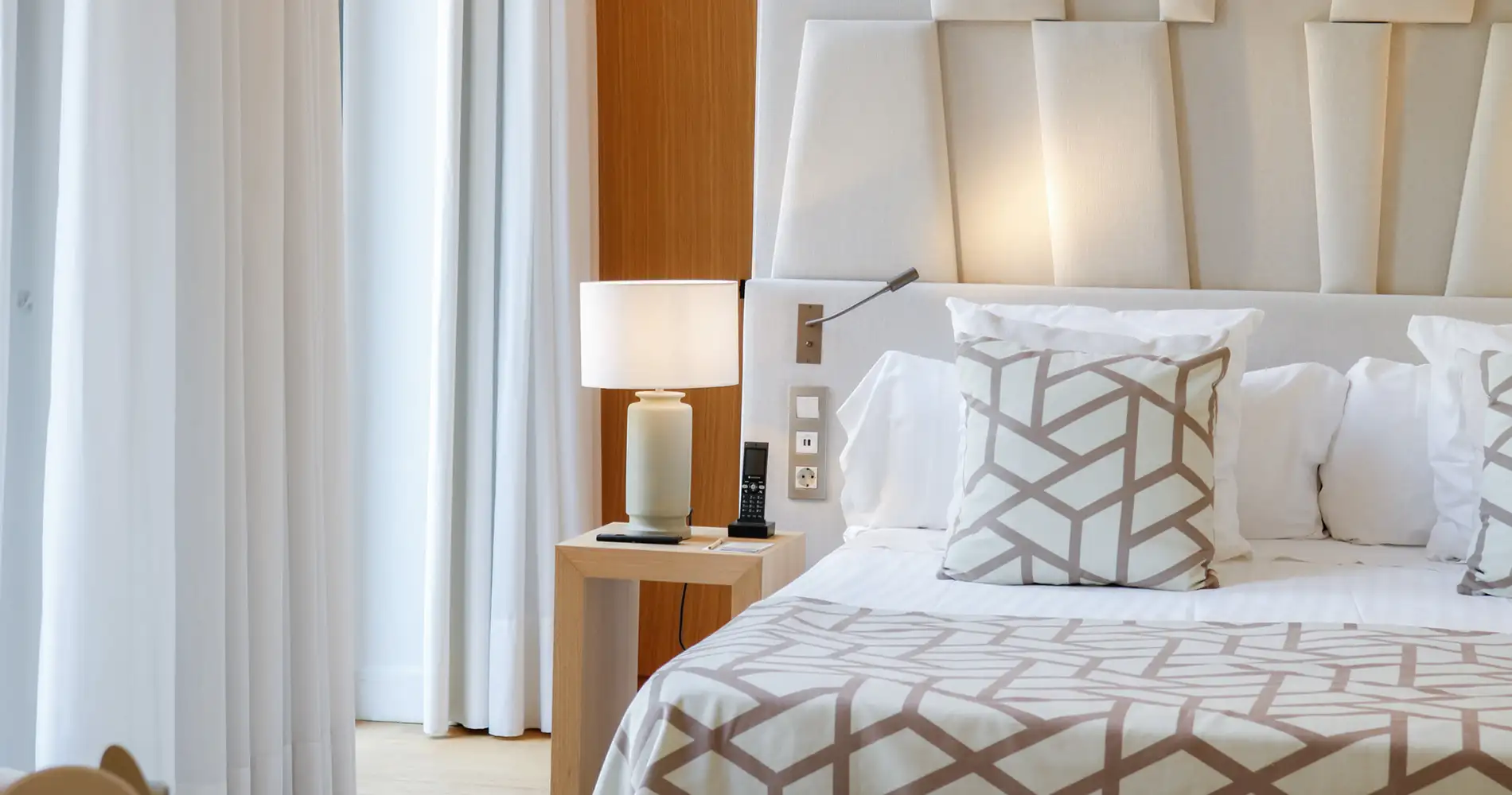 Habitaci&oacute;n de hotel moderna con cama, almohadas y l&aacute;mparas junto a la ventana