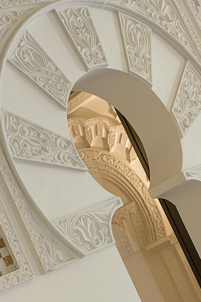 Detalle de columnas decoradas y arcos blancos con relieve ornamental.