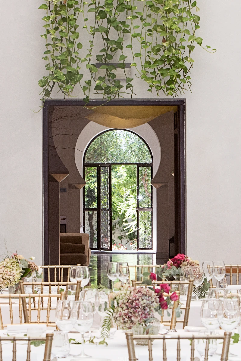 Entrada de sal&oacute;n con marco circular, puerta de jard&iacute;n y decoraci&oacute;n floral.
