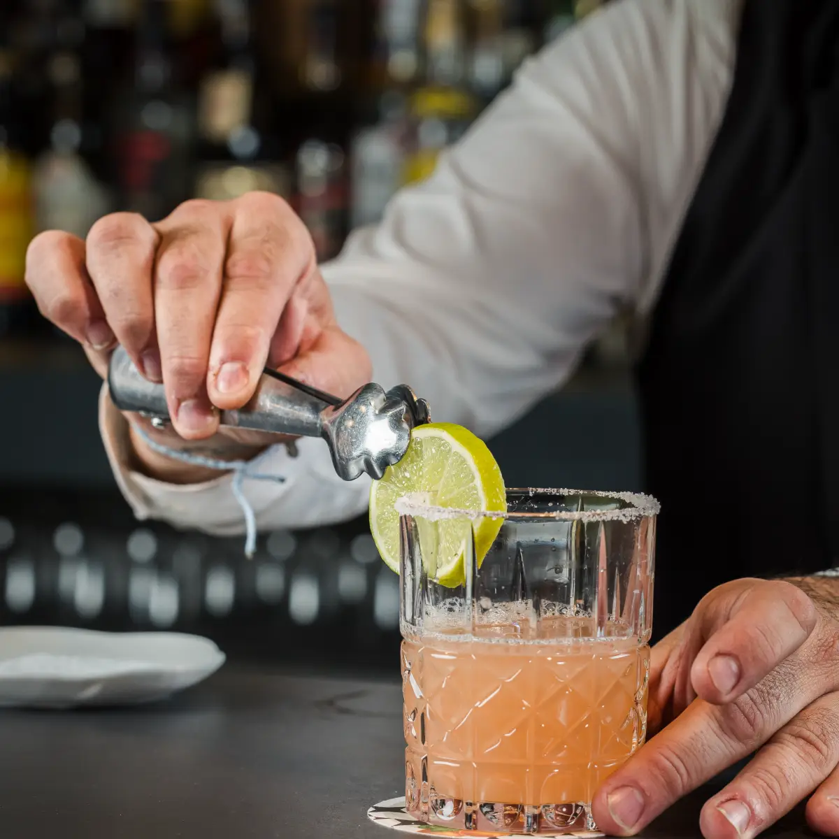 Barman exprime lim&oacute;n y sirve bebida en vaso con hielo