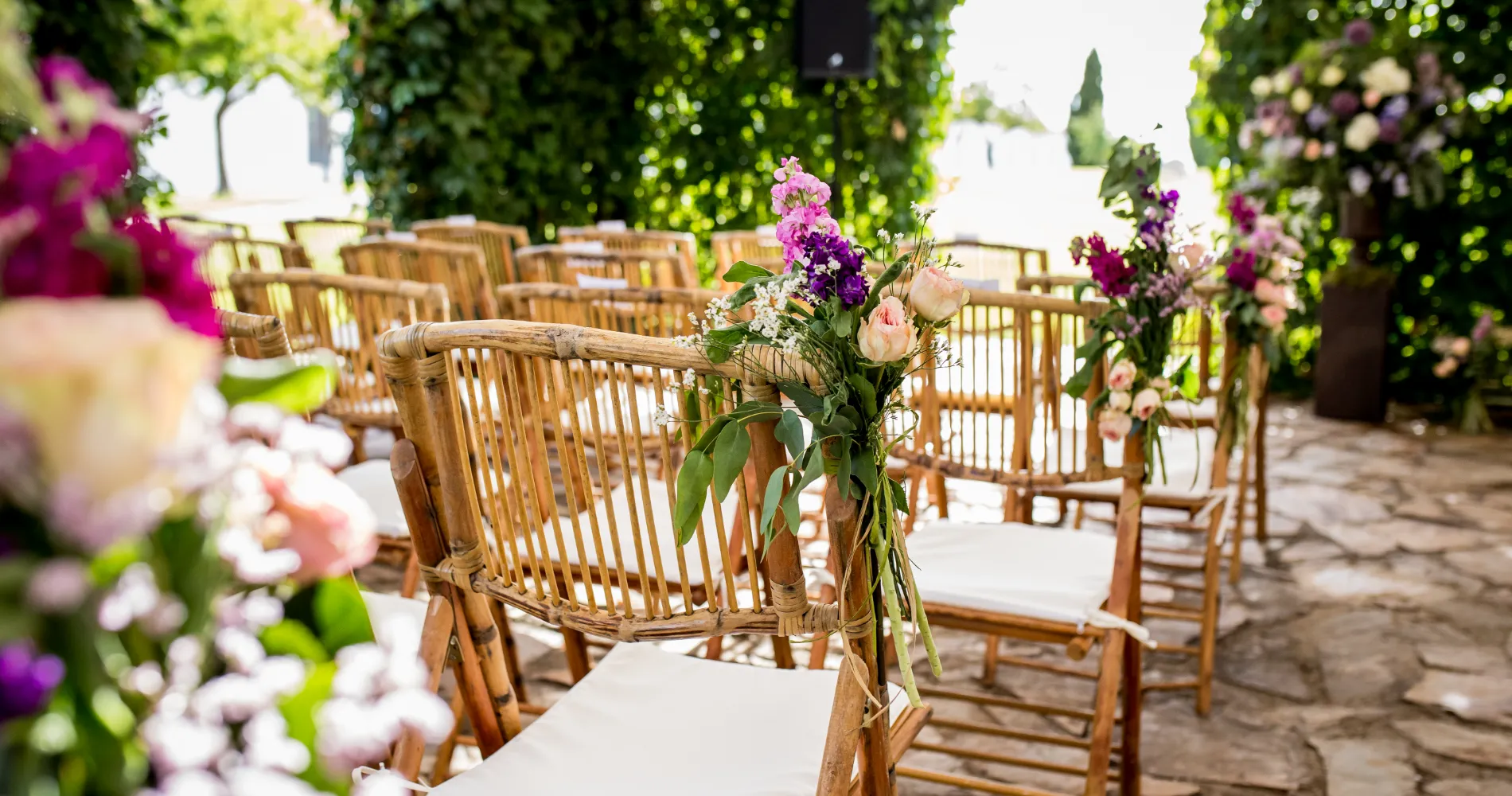 Arreglo floral en mesa con sillas de bamb&uacute; en jard&iacute;n al aire libre
