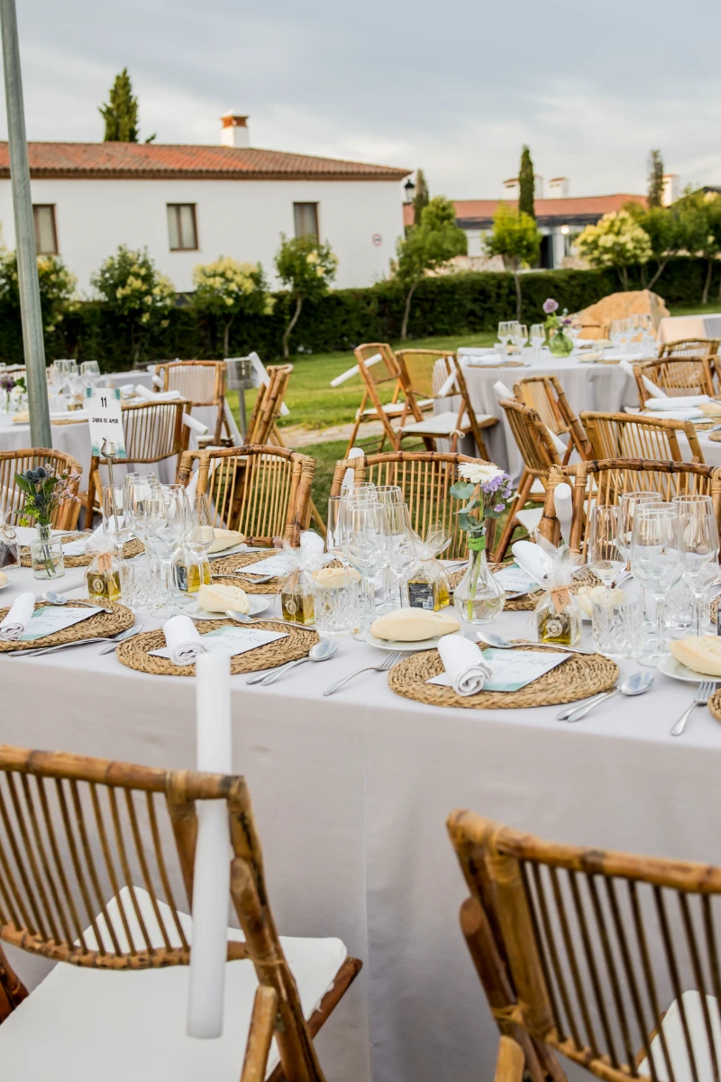 Mesa de banquete al aire libre con sillas de madera y vajilla preparada