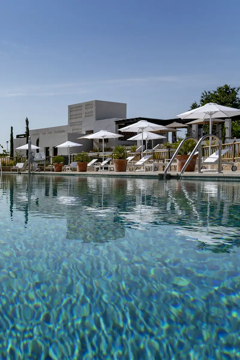 Piscina de hotel con paraguas blancos y edificio moderno al fondo