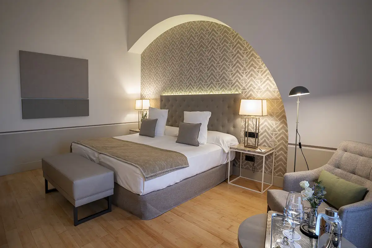 Habitaci&oacute;n moderna con cama doble, pared decorativa y l&aacute;mparas encendidas