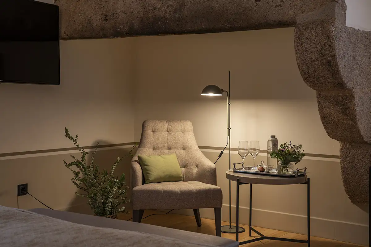 Sill&oacute;n beige con mesa auxiliar y l&aacute;mpara iluminada en habitaci&oacute;n moderna