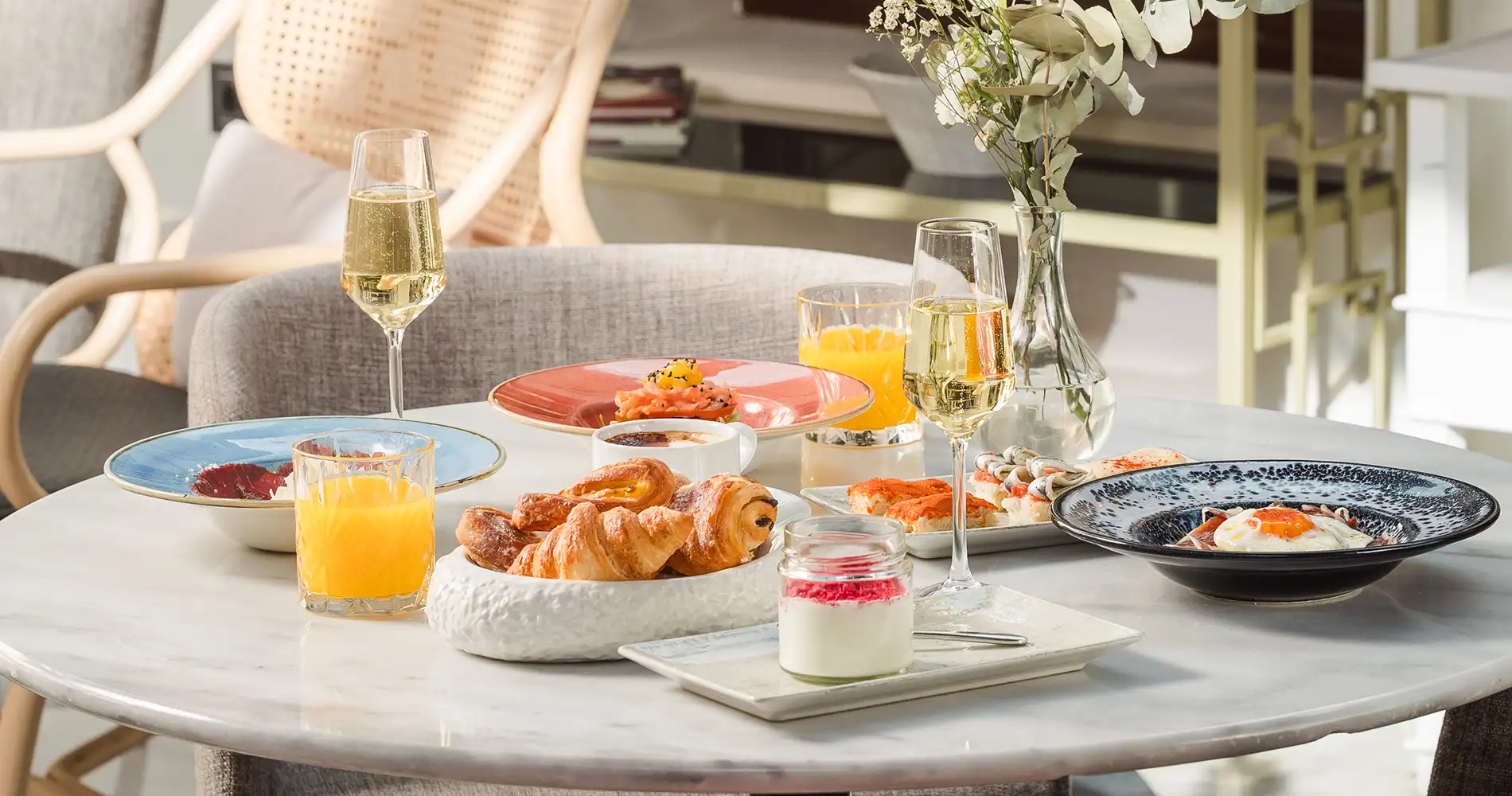 Mesa con platos y copas de vino blanco, desayuno brunch al sol