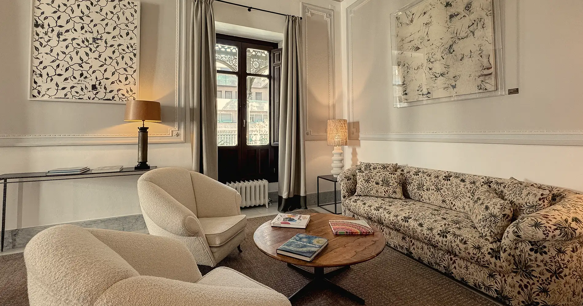 Sala de estar luminosa con sof&aacute;, sill&oacute;n, mesa y cortinas frente a ventana