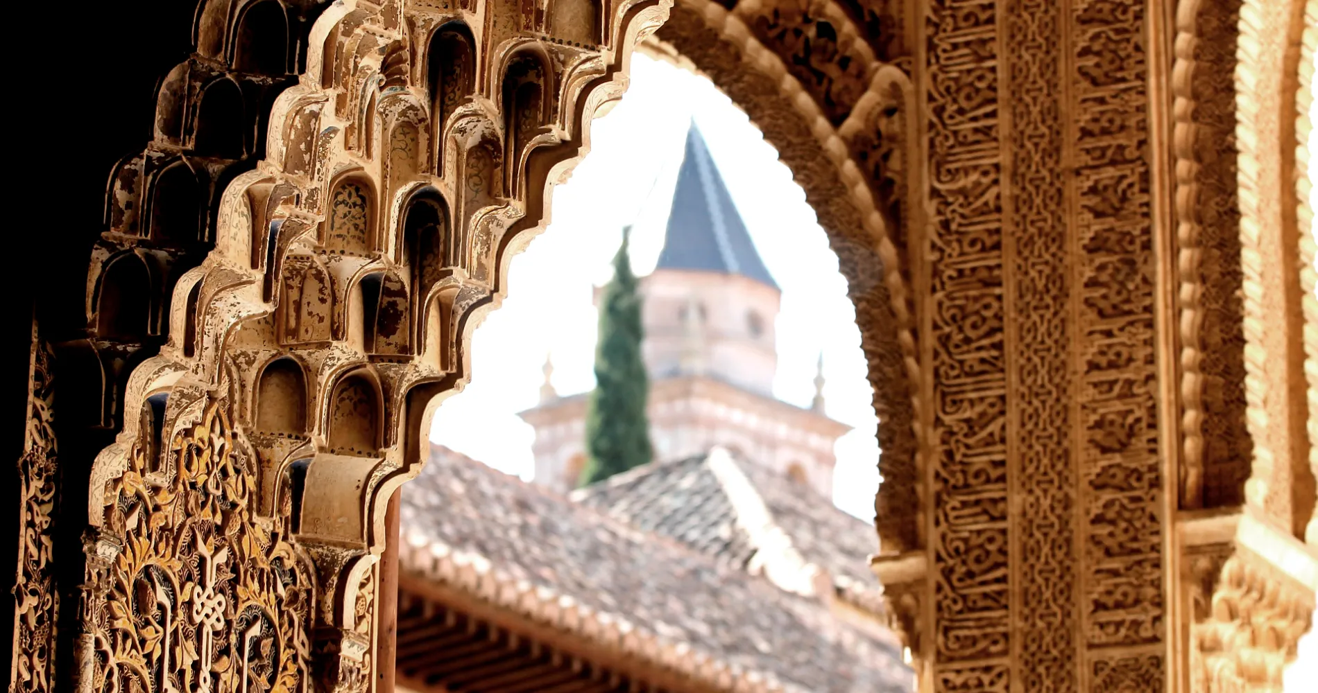Arcos tallados y azulejos dorados; mujer y domo desenfocados detr&aacute;s del arco