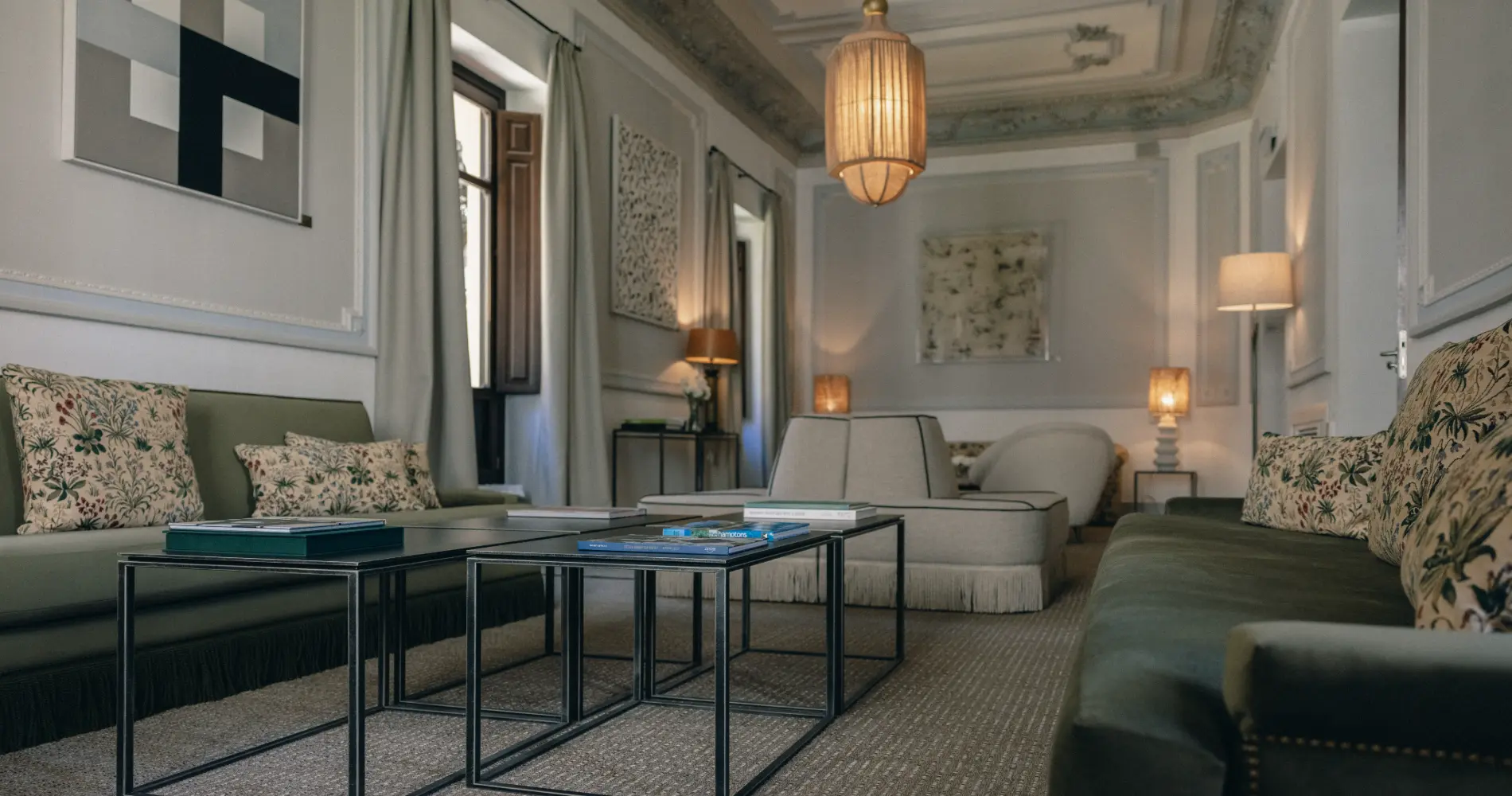 Sala de estar elegante con sof&aacute;s, mesa de centro y l&aacute;mpara colgante.