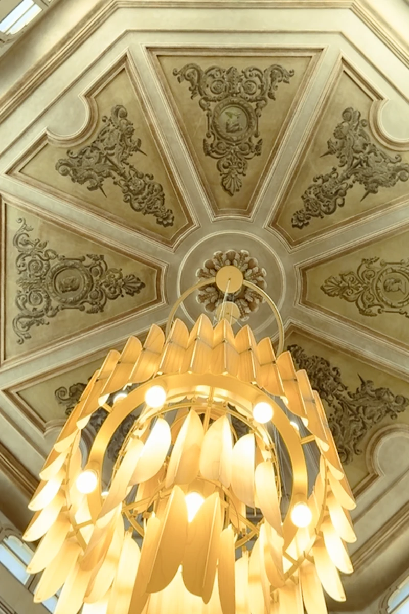 Techo ornamentado de un interior con l&aacute;mpara dorada colgante y luces