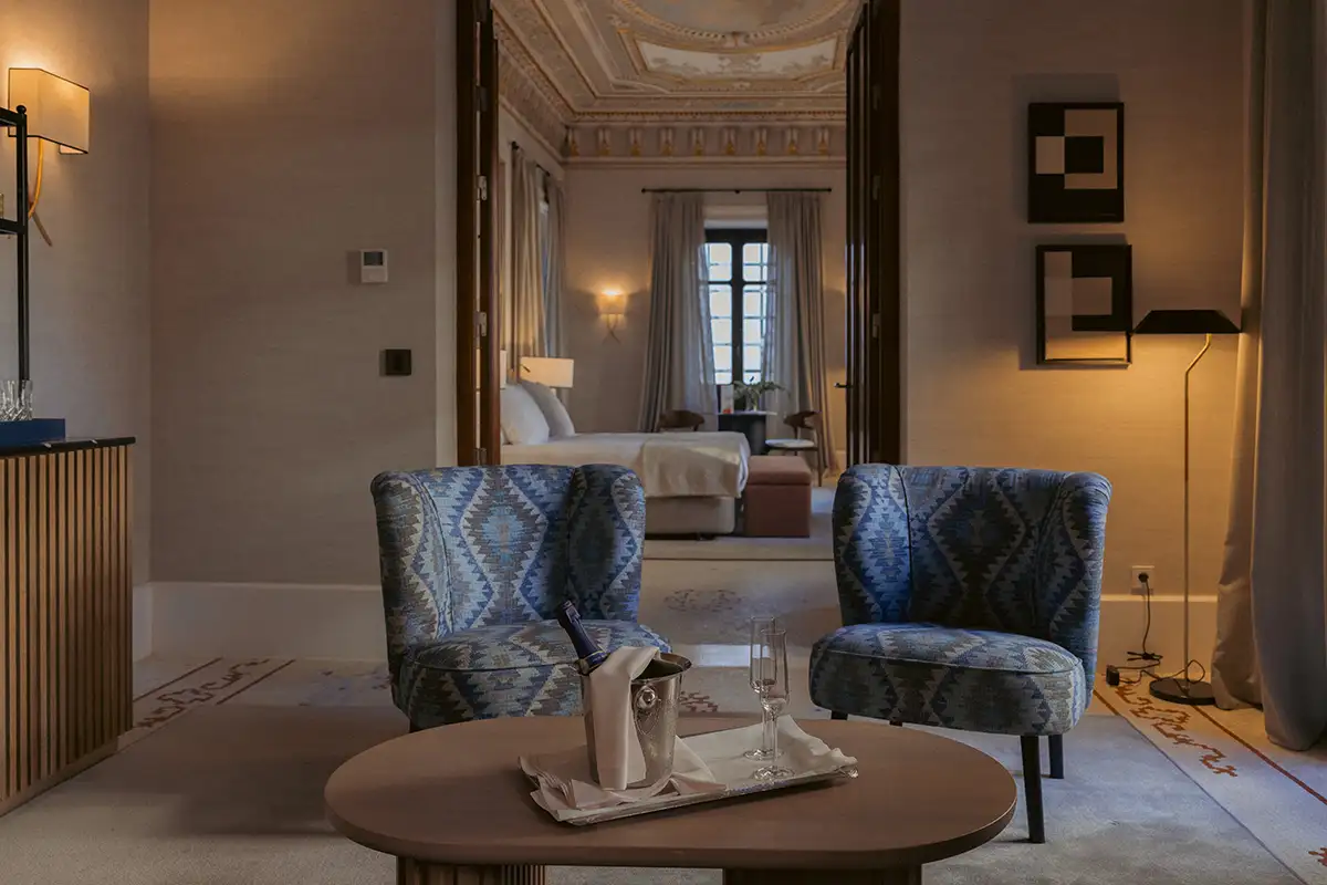 Sala de estar elegante con sillones azules y mesa redonda, luz c&aacute;lida.